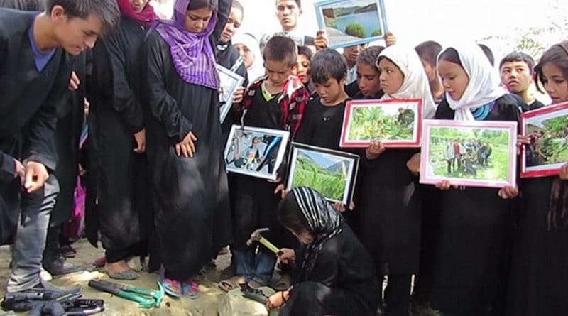 Sakina breaks a toy gun before burying it. Inam and other street kids await their turn.