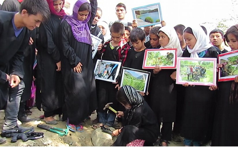 Sakina breaks a toy gun before burying it. Inam and other street kids await their turn.