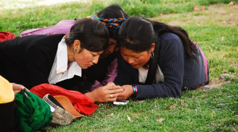 Tibetan women checking their cell phones. Photo by Tito Craige.