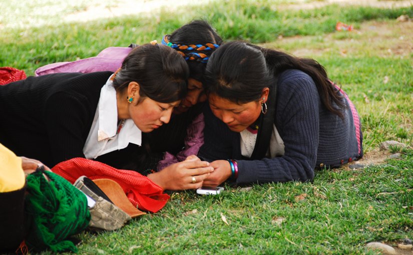 Tibetan women checking their cell phones. Photo by Tito Craige.