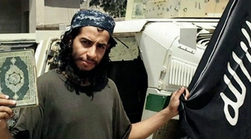 Abdelhamid Abaaoud holding the Quran and a black flag of the Islamic State. Photo Credit: Islamic State propaganda.