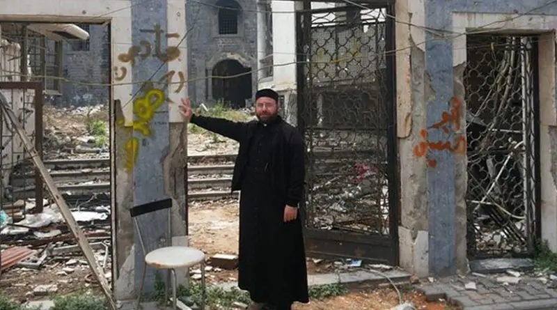 A priest stands before the ruins of St. Mary's Syriac Orthodox parish in Homs. Credit: Aid to the Church in Need.