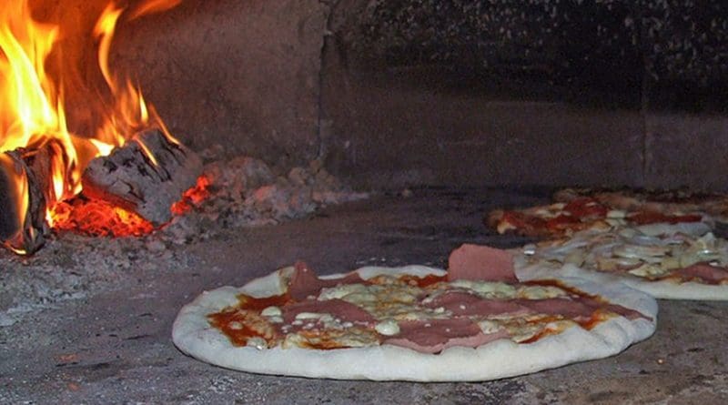 Pizzas bake in a traditional wood-fired brick oven. Photo by Claus Ableiter, Wikipedia Commons.