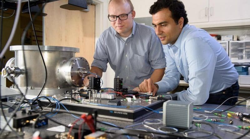 Post-doctoral scholar Peter McMahon, left, and visiting researcher Alireza Marandi examine a prototype of a new type of light-based computer. Credit L.A. Cicero