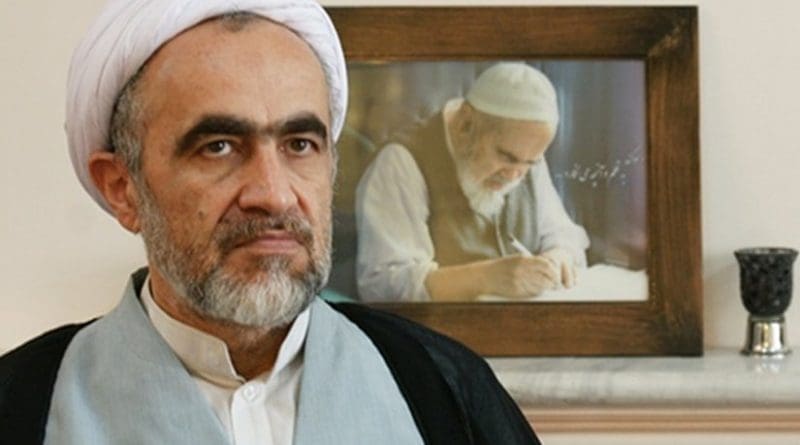 Ahmad Montazeri sits in front of a portrait picture of his late father Hossein Ali Montazeri. Photo via Radio Zamaneh.