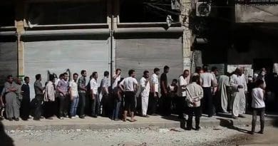 Aleppians waiting in a bread line during the Syrian civil war. File photo Voice of America News, Scott Bobb. Wikipedia Commons.