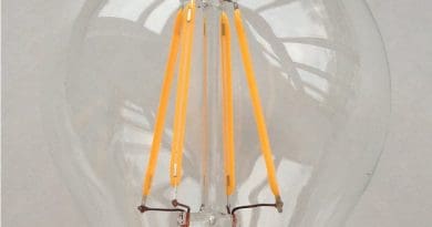 A 230-volt LED filament light bulb, with a B22 base. The filaments are visible as the four yellow vertical lines. Photo by Henk Muller, Wikipedia Commons.