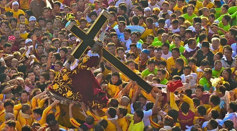 Marshals in yellow lift the Black Nazarene onto its ándas at the start of the Traslación in Manila, Philippines. Photo by Jsinglador, Wikipedia Commons.