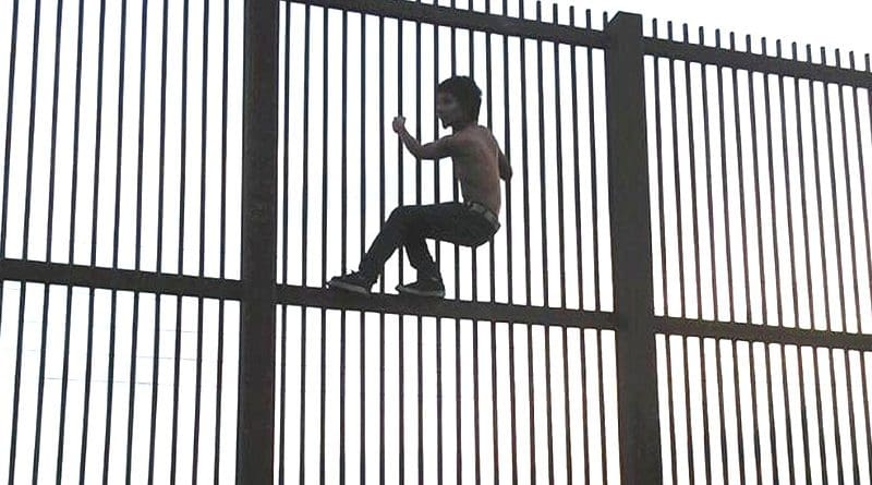 Climbing the Mexico–United States barrier fence in Brownsville, Texas. Photo by Nofx221984, Wikipedia Commons.