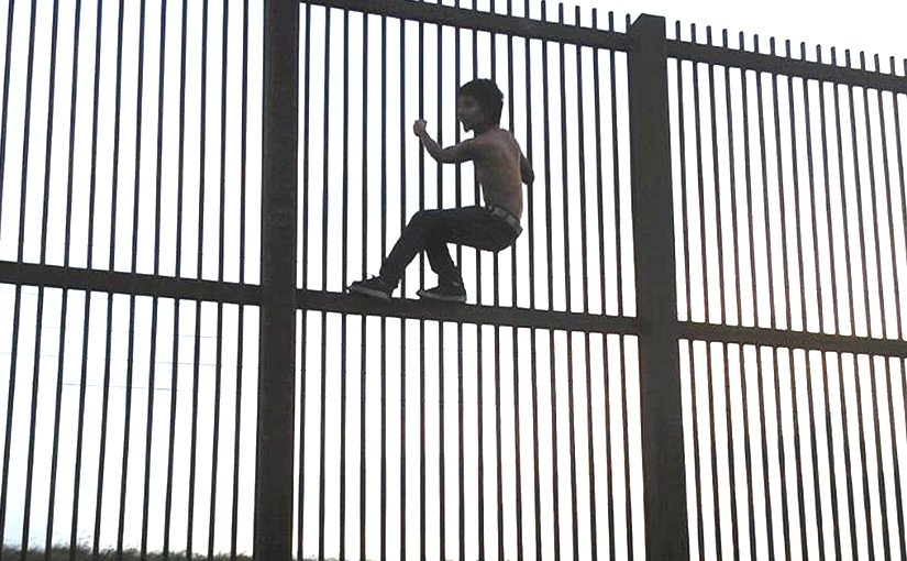 Climbing the Mexico–United States barrier fence in Brownsville, Texas. Photo by Nofx221984, Wikipedia Commons.