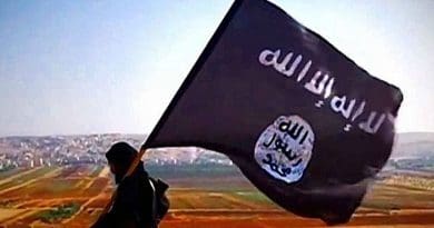 A ISIL fighter carrying the militant group's flag on Tall Dabiq which overlooks the town of Dabiq, Syria. File Photo Credit: VOA, Wikipedia Commons.