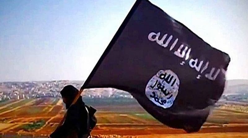 A ISIL fighter carrying the militant group's flag on Tall Dabiq which overlooks the town of Dabiq, Syria. File Photo Credit: VOA, Wikipedia Commons.