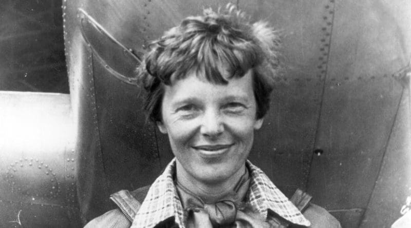 Amelia Earhart standing under nose of her Lockheed Model 10-E Electra. Photo Credit: Wikimedia Commons.