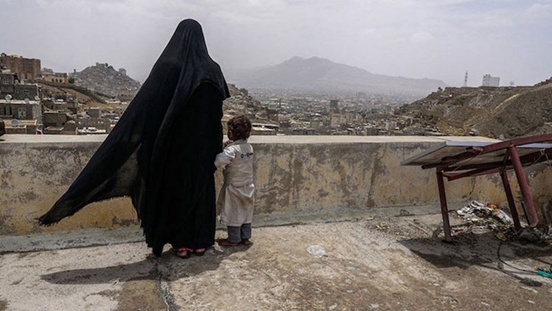 An internally displaced woman and her daughter look over the city of Sana’a, Yemen, from the roof of this dilapidated building they call their new home. Photo: Giles Clarke/UN OCHA