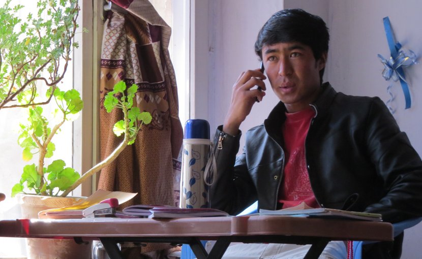 Ghulam at his study desk in Kabul, calling to make sure his family members were well, in the minutes following a bomb blast nearby