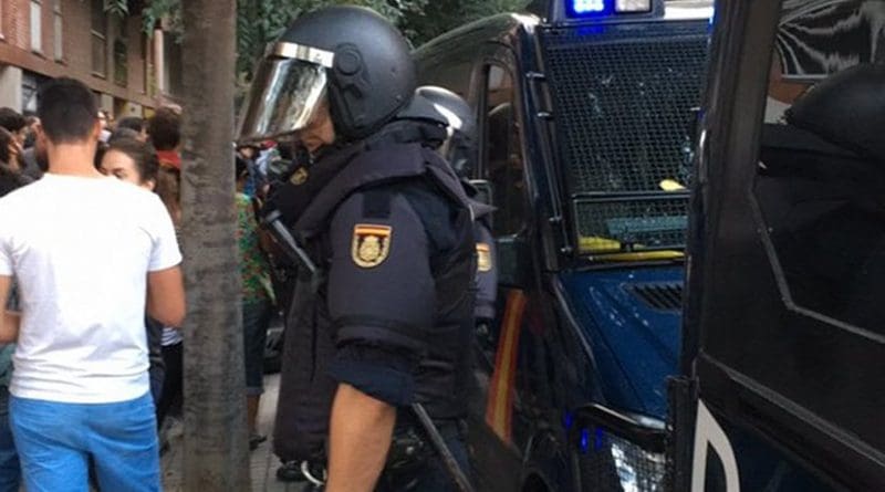 A Spanish officer of the National Police Corps in front of the headquarters of the Catalan political party Popular Unity Candidacy. File photo by Gerhidt, Wikipedia Commons.