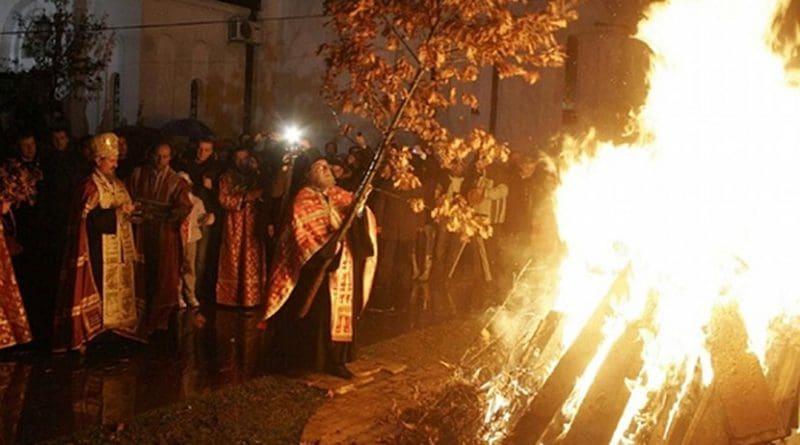 A Serbian Orthodox priest places the badnjak on a fire during a Christmas Eve celebration at the Cathedral of Saint Sava in Belgrade. Photo Credit: Lazar, Wikipedia Commons.