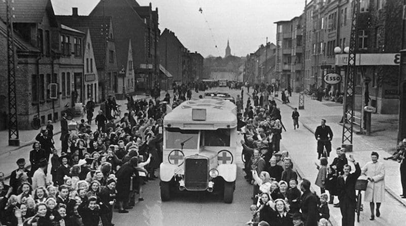 As part of Count Folke Bernadotte action, Danish Red Cross buses drive through Odense on the way to Sweden, carrying Danish prisoners from German concentration camps April 17, 1945. CC BY-SA 2.0.