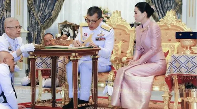 Thailand's King Maha Vajiralongkorn signs marriage registration documents while Queen Suthida looks on. Photo Credit: Thailand Bureau of the Royal Household
