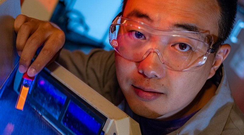 Rice University graduate student Bo Jiang shows a fluorescing vial of soluble amyloid beta peptide aggregates implicated in the onset of Alzheimer's disease. The peptides are tagged and tracked with a ruthenium complex developed at Rice that can monitor them in lab experiments as they grow over time. Credit Jeff Fitlow/Rice University