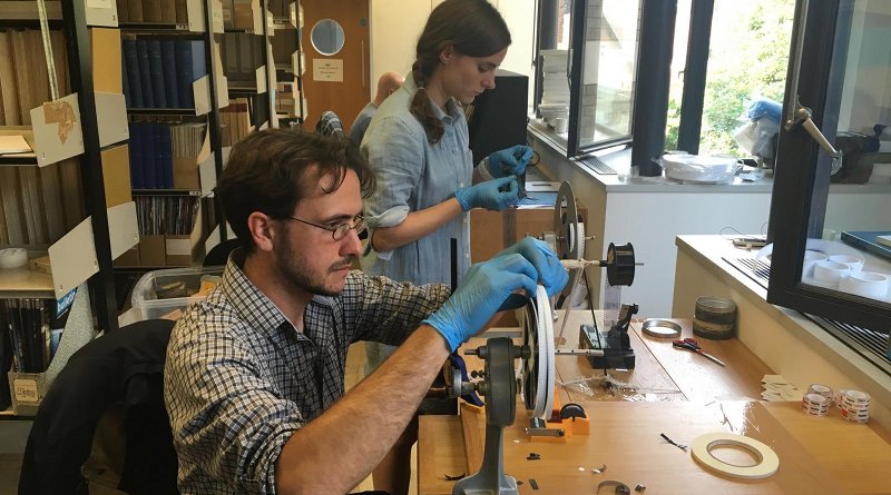 Professor Dustin Schroeder (foreground) and art historian Jessica Daniel splice 50-year-old film containing radar measurements of Antarctica into a reel in preparation for digital scanning at the Scott Polar Research Institute in the UK. Credit Courtesy of Dustin Schroeder