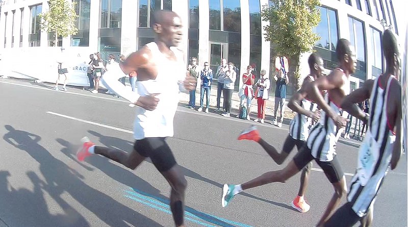 Eliud Kipchoge (left) and his three pacemakers (right) about 30 minutes into the run, during the Marathon world record in the 2018 Berlin Marathon. He is shown a few seconds before crossing the river Spree. Photo Credit: C.Suthorn, Wikipedia Commons