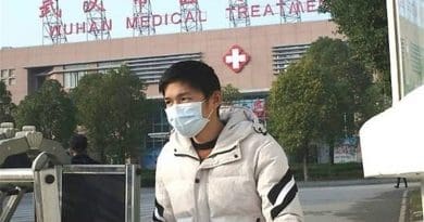 Man wearing mask in front of a hospital in Wuhan, China. Photo Credit: Tasnim News Agency
