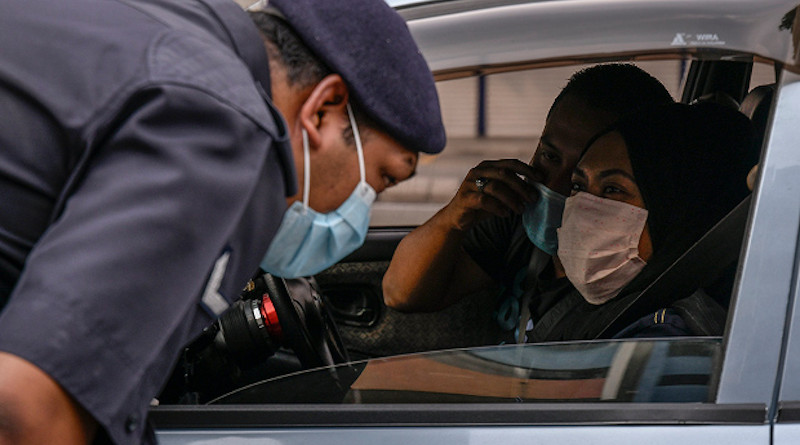 A Malaysian police officer questions a driver at a coronavirus roadblock in Kuala Lumpur, March 19, 2020.S. Mahfuz/BenarNews