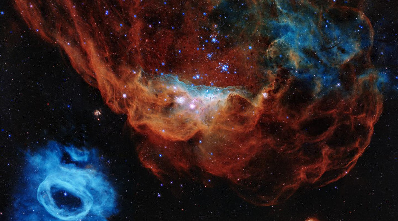 A colorful image resembling a cosmic version of an undersea world teeming with stars is being released to commemorate the Hubble Space Telescope's 30 years of viewing the wonders of space. In the Hubble portrait, the giant red nebula (NGC 2014) and its smaller blue neighbor (NGC 2020) are part of a vast star-forming region in the Large Magellanic Cloud, a satellite galaxy of the Milky Way, located 163,000 light-years away. The image is nicknamed the "Cosmic Reef," because NGC 2014 resembles part of a coral reef floating in a vast sea of stars. Some of the stars in NGC 2014 are monsters. The nebula's sparkling centerpiece is a grouping of bright, hefty stars, each 10 to 20 times more massive than our sun. The seemingly isolated blue nebula at lower left (NGC 2020) has been created by a solitary mammoth star 200,000 times brighter than our sun. The blue gas was ejected by the star through a series of eruptive events during which it lost part of its outer envelope of material. CREDIT NASA, ESA and STScI