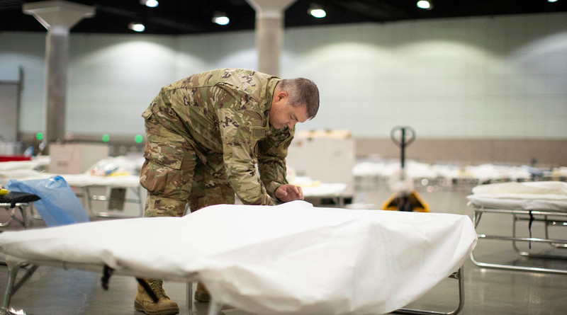 An airman with the California Air National Guard sets up a hospital bed in a medical station inside the Los Angeles Convention Center, March 29, 2020. Photo Credit: Air Force Staff Sgt. Crystal Housman