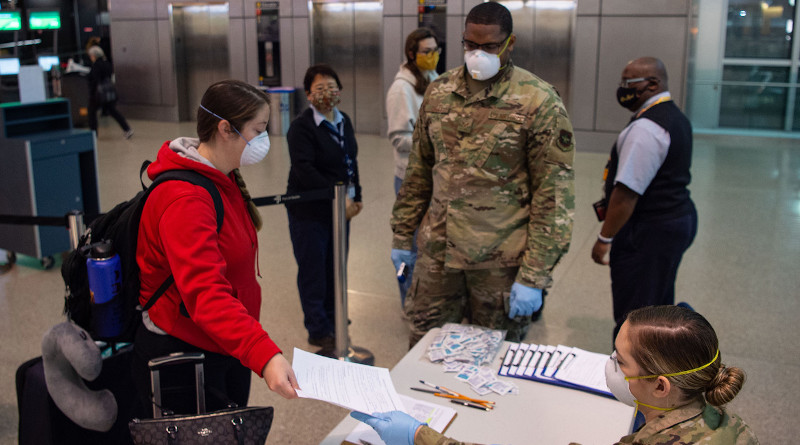 A passenger traveling to Asia hands a medical questionnaire to Air Force Airman 1st Class Nicole Mourik, a passenger service specialist with the 62nd Aerial Port Squadron at the Seattle-Tacoma International Airport in Seattle, April 30, 2020. To prevent the spread of COVID-19, passengers must answer questions about their current health, where they have traveled recently and whether they work in a medical facility. Photo Credit: Air Force Senior Airman Tryphena Mayhugh