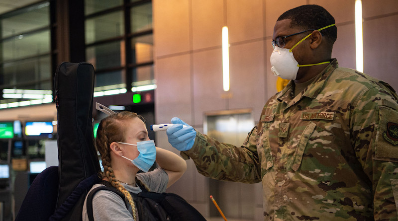 Air Force Senior Airman Kevin Gray II, a passenger service specialist with the 62nd Aerial Port Squadron, takes the temperature of a passenger traveling to Asia at the Seattle-Tacoma International Airport in Seattle, April 30, 2020. Passengers with a fever of 100.4 degrees or higher are denied travel as a precaution against the spread of COVID-19. Photo Credit: Air Force Senior Airman Tryphena Mayhugh