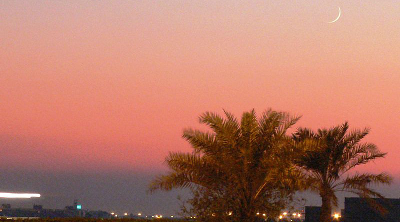 A crecent moon can be seen over palm trees at sunset in Manama, Bahrain, marking the beginning of the Muslim month of Ramadan. Photo Credit: Ahmed Rabea, Wikipedia Commons