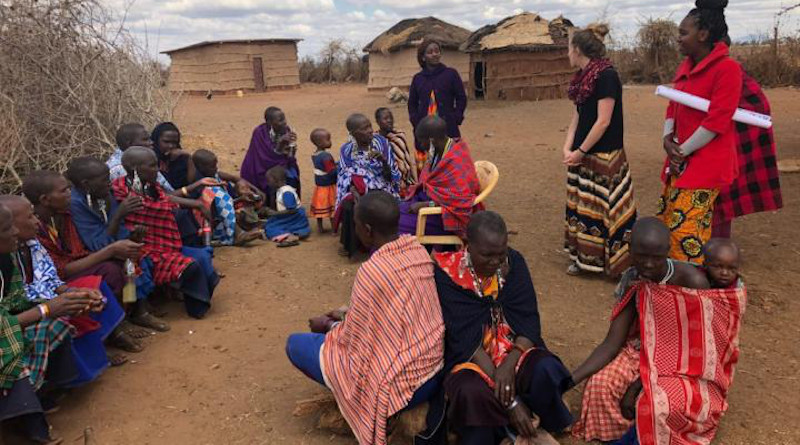 Researchers conduct a group interview about mobile phone use and empowerment with Maasai women in northern Tanzania in 2018. Standing, left to right: research assistant Felista Terta, lead researcher Kelly Summers, and research assistant Naomi Peter. Photo by Timothy Baird, Virginia Tech. CREDIT: Virginia Tech