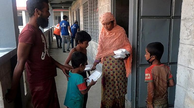 A Rohingya refugee distributes food packages to her children in front of their new home in Bhashan Char, Bangladesh, Dec. 5, 2020. Photo Credit: BenarNews