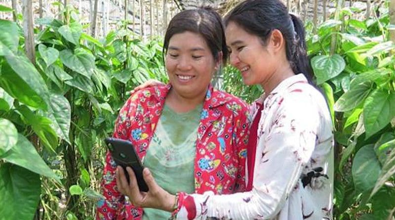Two women look at a smartphone. Photo credit: UNCDF