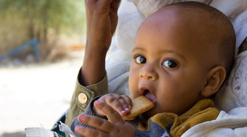 A seven-month-old baby displaced with his mother due to conflict in Tigray eats a high energy biscuit to boost his nutrition levels. Credit: UNICEF/Esiey Leul Kinfu