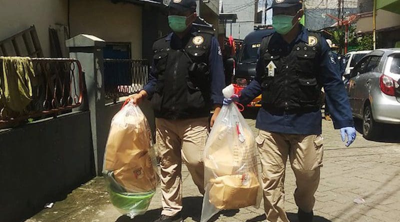 Two police officers carry plastic bags containing items recovered from the Makassar-area home of a couple suspected of carrying out a suicide bombing outside a church in Makassar on Palm Sunday, March 29, 2021. Yayank Stiv/BenarNews