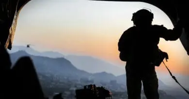 Army loadmaster stands on the rear ramp of a CH-47F Chinook and watches the sunset as the helicopter flies over Kabul, Afghanistan. Photo Credit: Julie A. Kelemen, DOD