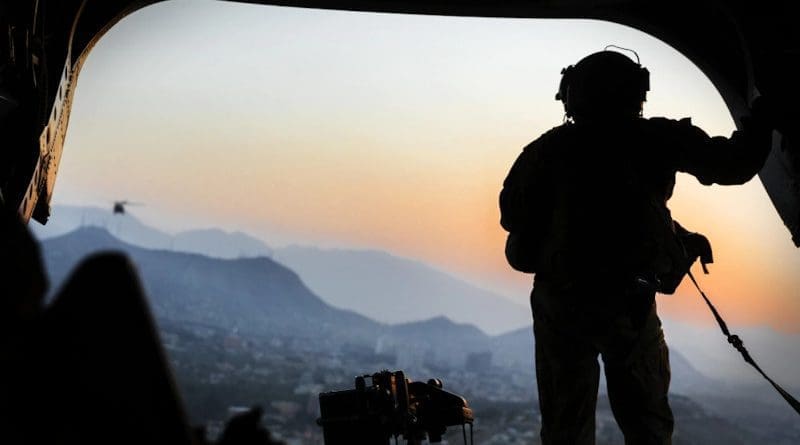 Army loadmaster stands on the rear ramp of a CH-47F Chinook and watches the sunset as the helicopter flies over Kabul, Afghanistan. Photo Credit: Julie A. Kelemen, DOD