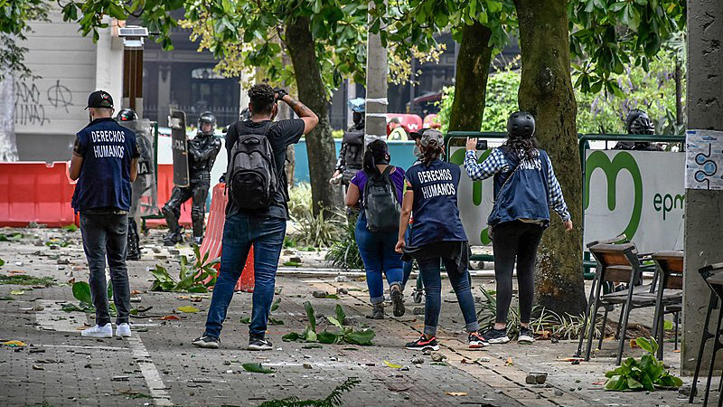 Members of Defensores de Derechos Humanos (DDHH) try to hold talks with Colombian ESMAD police during protests. Photo Credit: Humano Salvaje, Wikipedia Commons