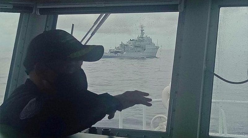 A Philippine Coast Guard officer aboard the BRP Cabra observes a Chinese Navy warship near the Marie Louise Bank in the South China Sea, July 13, 2021. Courtesy Philippine Coast Guard