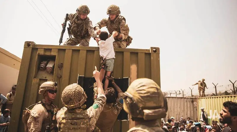 U.S. Marines, along with British and Turkish forces assist a child during an evacuation at Hamid Karzai International Airport, Kabul, Afghanistan, Aug. 20, 2021. U.S. service members are assisting the Department of State with a non-combatant evacuation operation (NEO) in Afghanistan. Photo Credit: Marine Corps Staff Sgt. Victor Mancilla