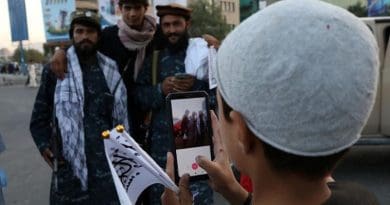 A young boy takes a photo of members of Taliban in Afghanistan. Photo Credit: Fars News Agency