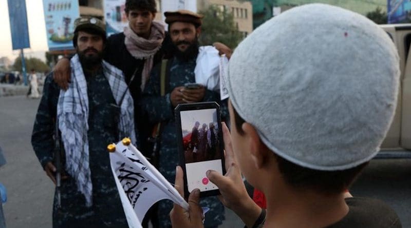 A young boy takes a photo of members of Taliban in Afghanistan. Photo Credit: Fars News Agency