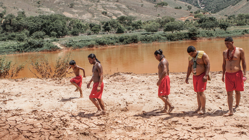 Krenak youths on the shore of the Doce River in the aftermath of Brazil’s worst environmental disaster: the collapse of a tailings dam in the municipality of Mariana, in Minas Gerais state, in 2015. The toxic sludge left the river unusable, affecting the culture, safety, and food and water supply for the Krenak Indigenous people and thousands of others. Image courtesy of Nicoló Lanfranchi/Greenpeace.