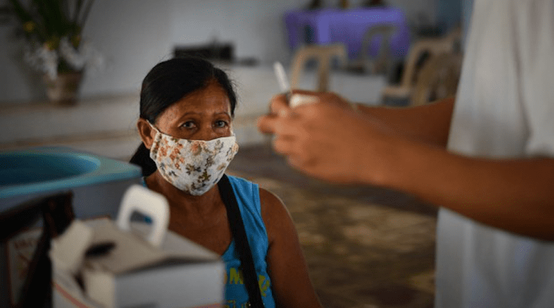 A woman waits to receive a COVID-19 vaccine shot in Bani, Philippines. Photo Credit: Jojo Riñoza/BenarNews
