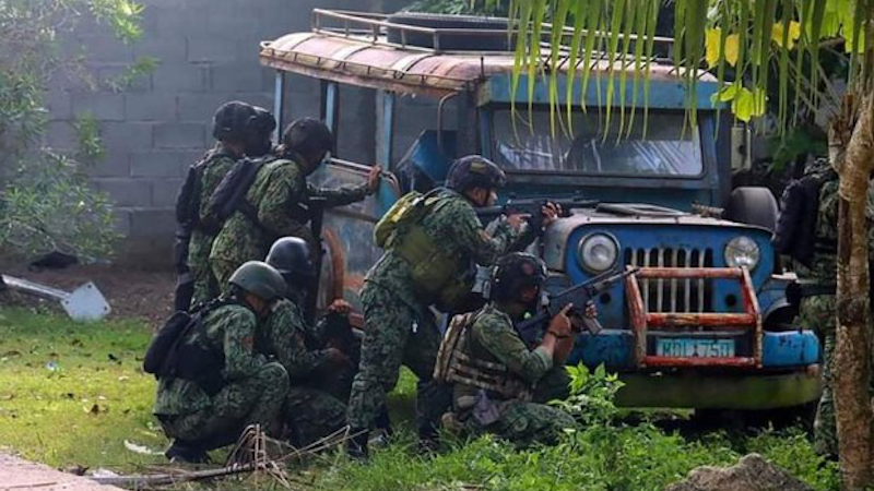 Police take position behind a parked vehicle during a raid that left six dead in Pikit, Cotabato province, southern Philippines, Dec. 29, 2021. Photo Credit: Philippine National Police handout