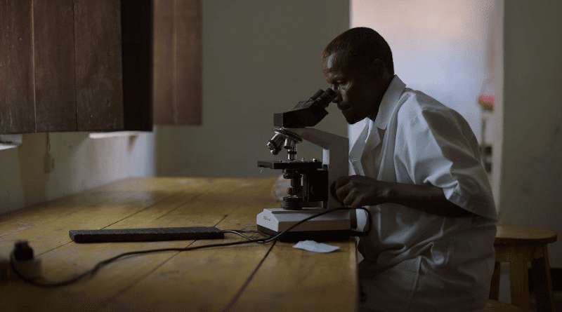 A lab technician checks a blood sample for malaria in Barawe, Somalia. Copyright: AMISOM photo / Tobin Jones, Public Domain