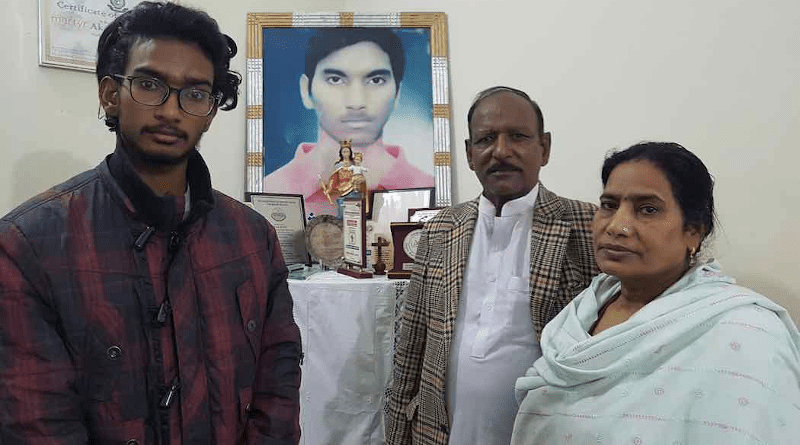 Akash Bashir's younger brother Ramish (left) with his father Bashir Emmanuel and mother Naz Bano inside their home near a picture of Akash. (Photo: Kamran Chaudhry)